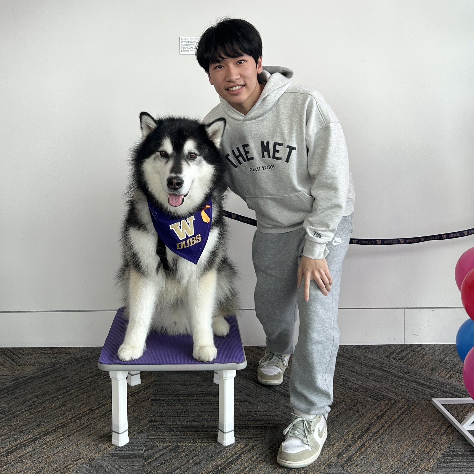 Student standing next to Dubs, the UW mascot.