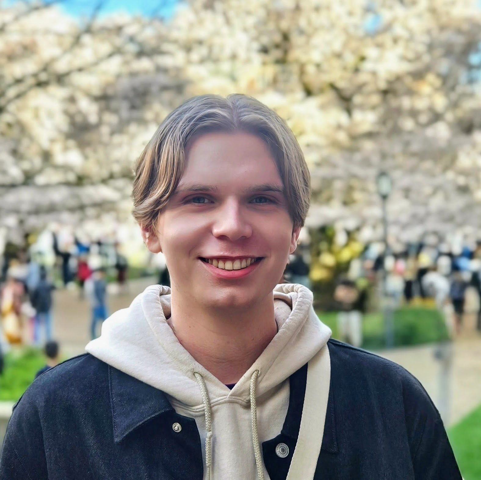 Headshot of Reese Fairchild, in front of the UW cherry blossoms.