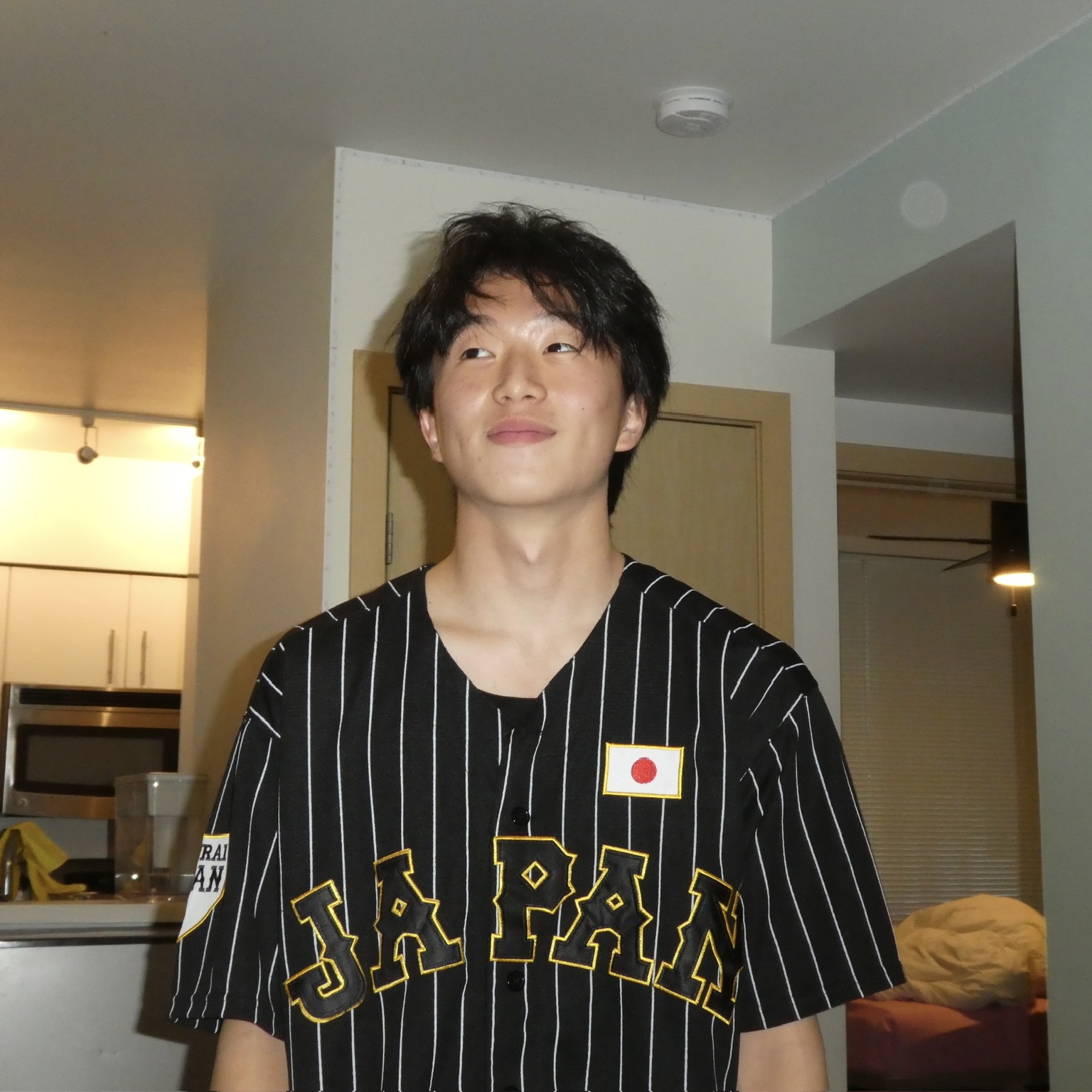 Headshot of TJ wearing a black pinstripe Team Japan baseball jersey