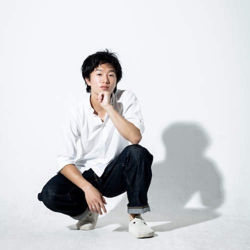 TJ is an east asian guy with black eyes and hair in wolfcut-ish style. He is wearing his default outfit \#7 which is jeans and a collared shirt.