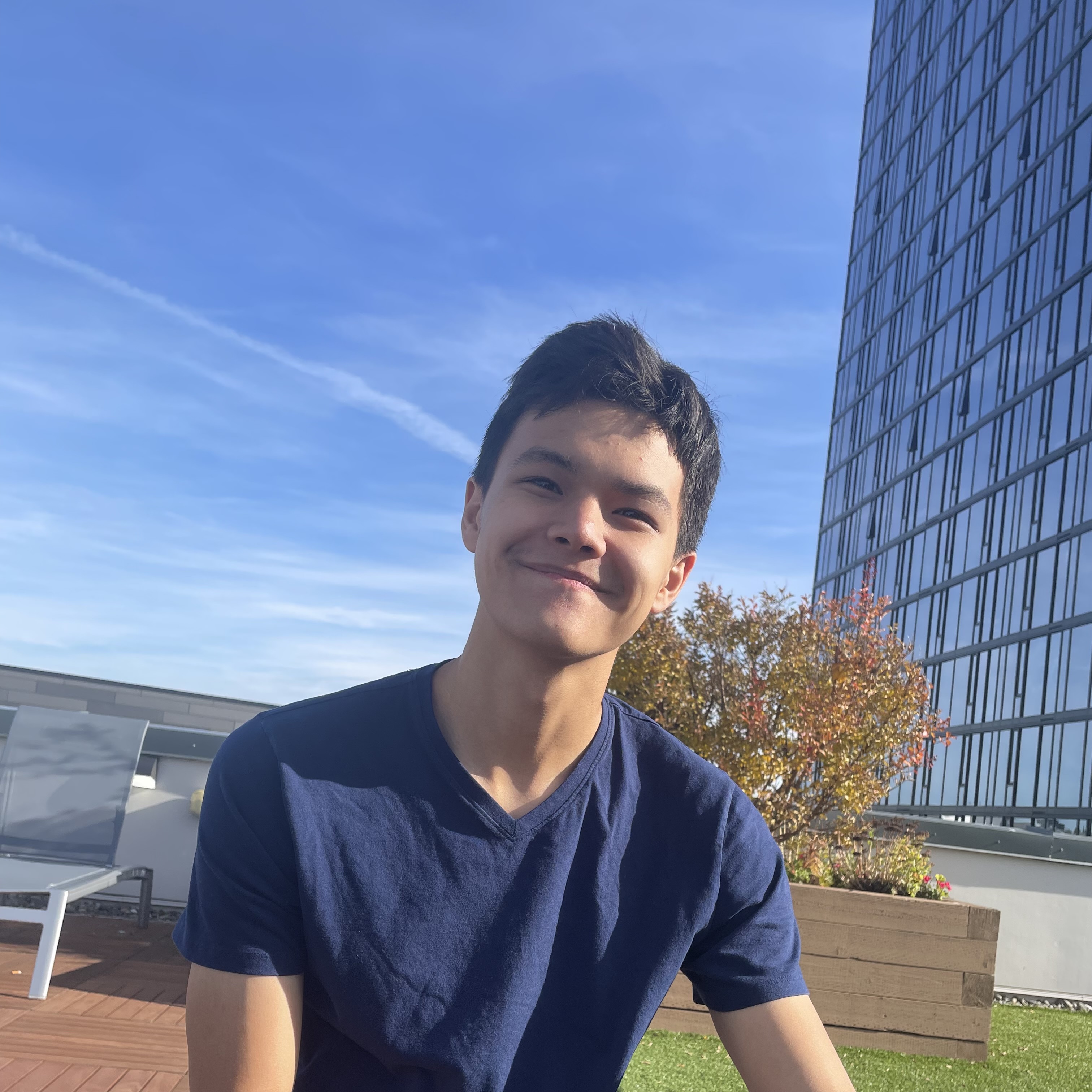 Aki sits and smiles on a sunny rooftop.