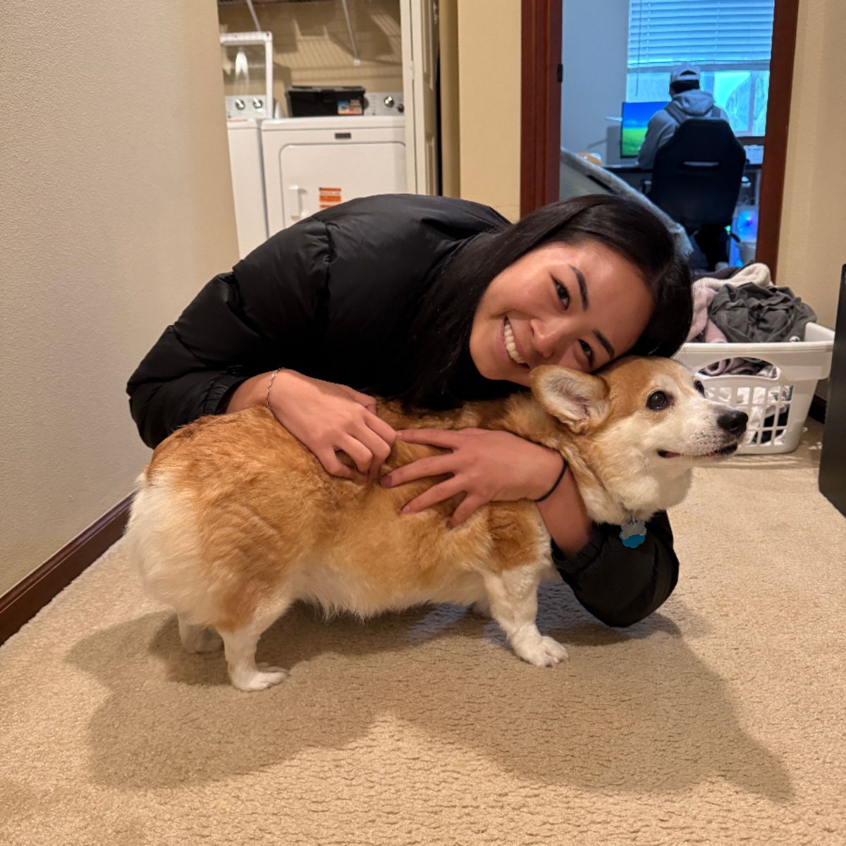 Shayna smiling while hugging a corgi