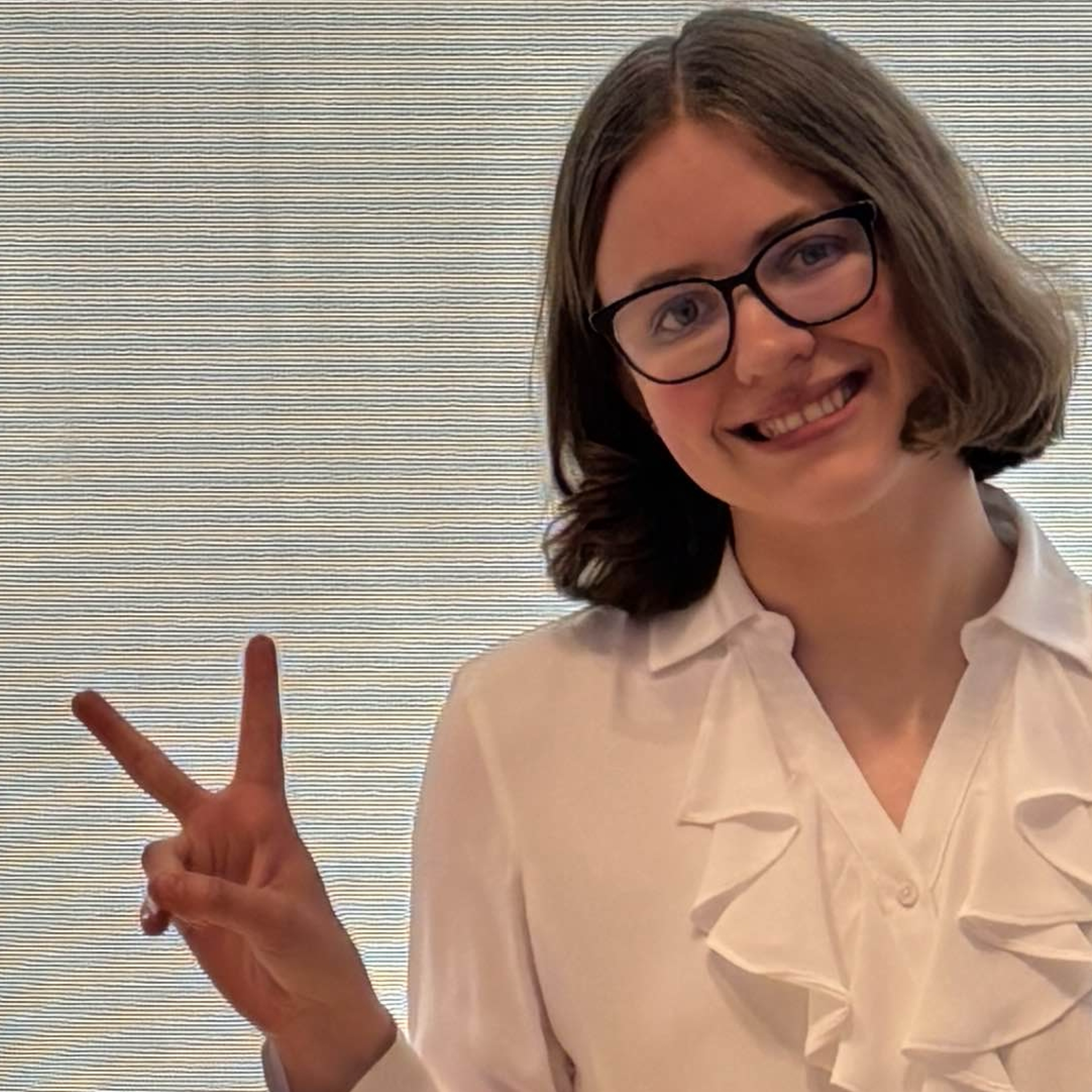 A close-up photo of Tamsyn Henke smiling and making a peace sign.