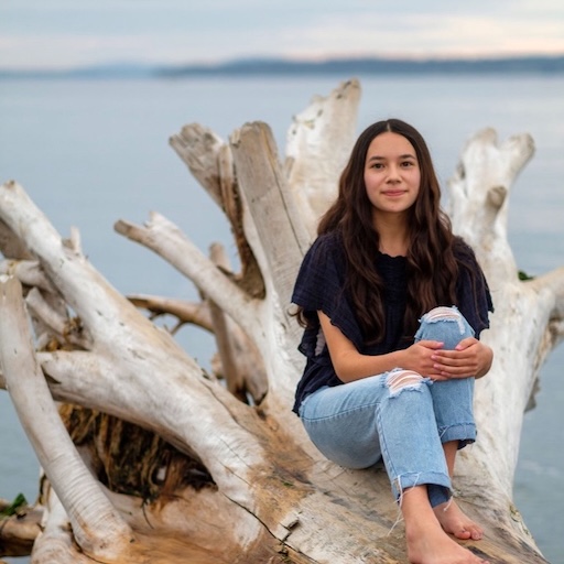 Chloë sitting on drift wood at the beach