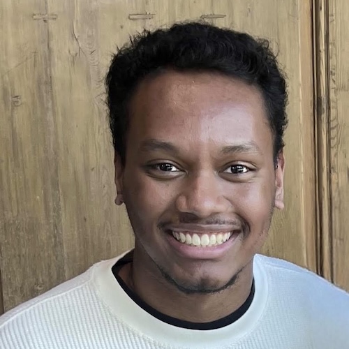 Close-up of Trey smiling brightly wearing an off-white sweater