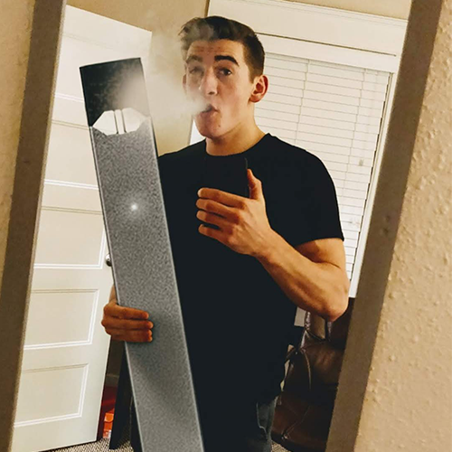 A mirror selfie of me taking a hit of a juul which has been enlarged
