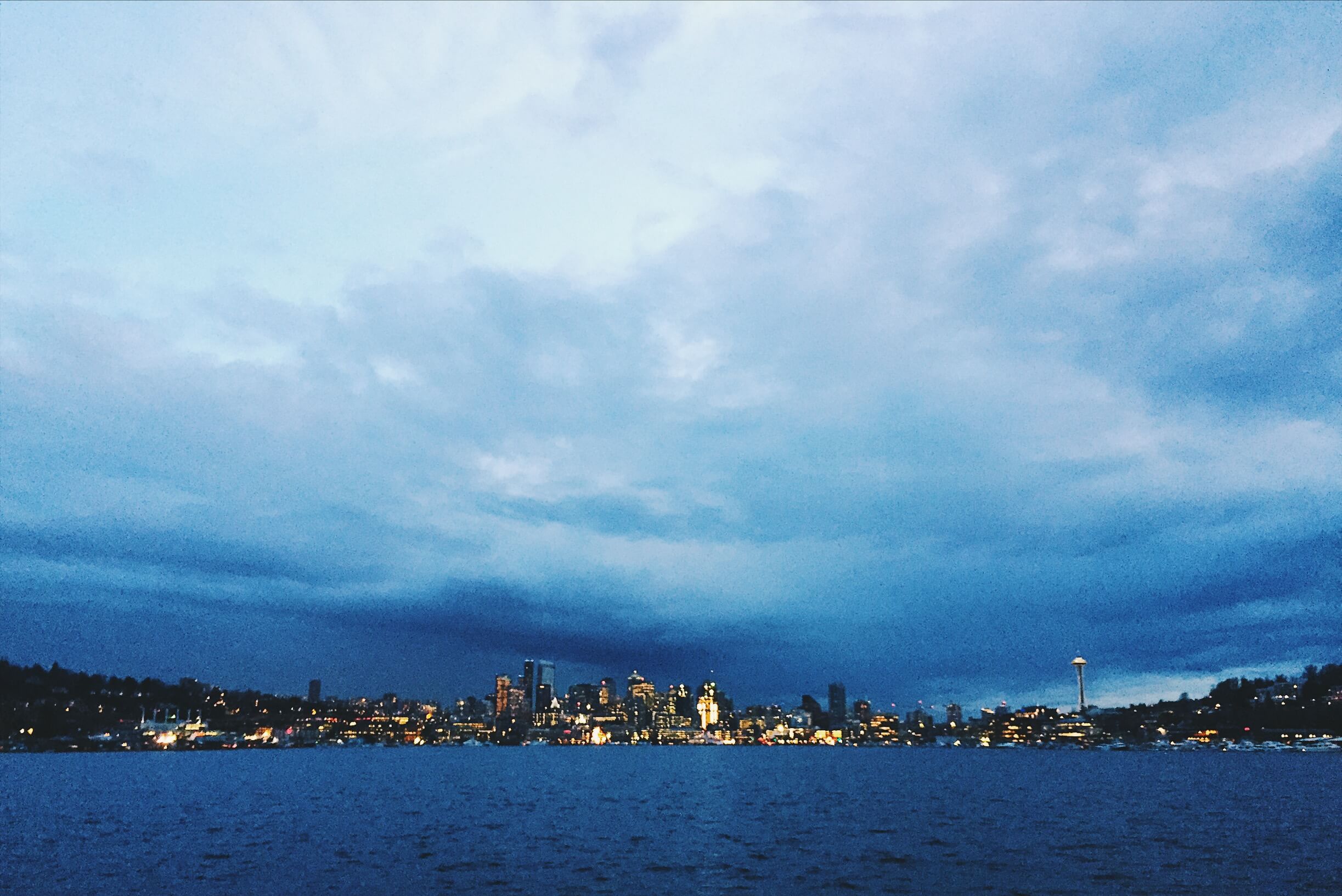 The city of Seattle across the water, on a dark and cloudy
              day.