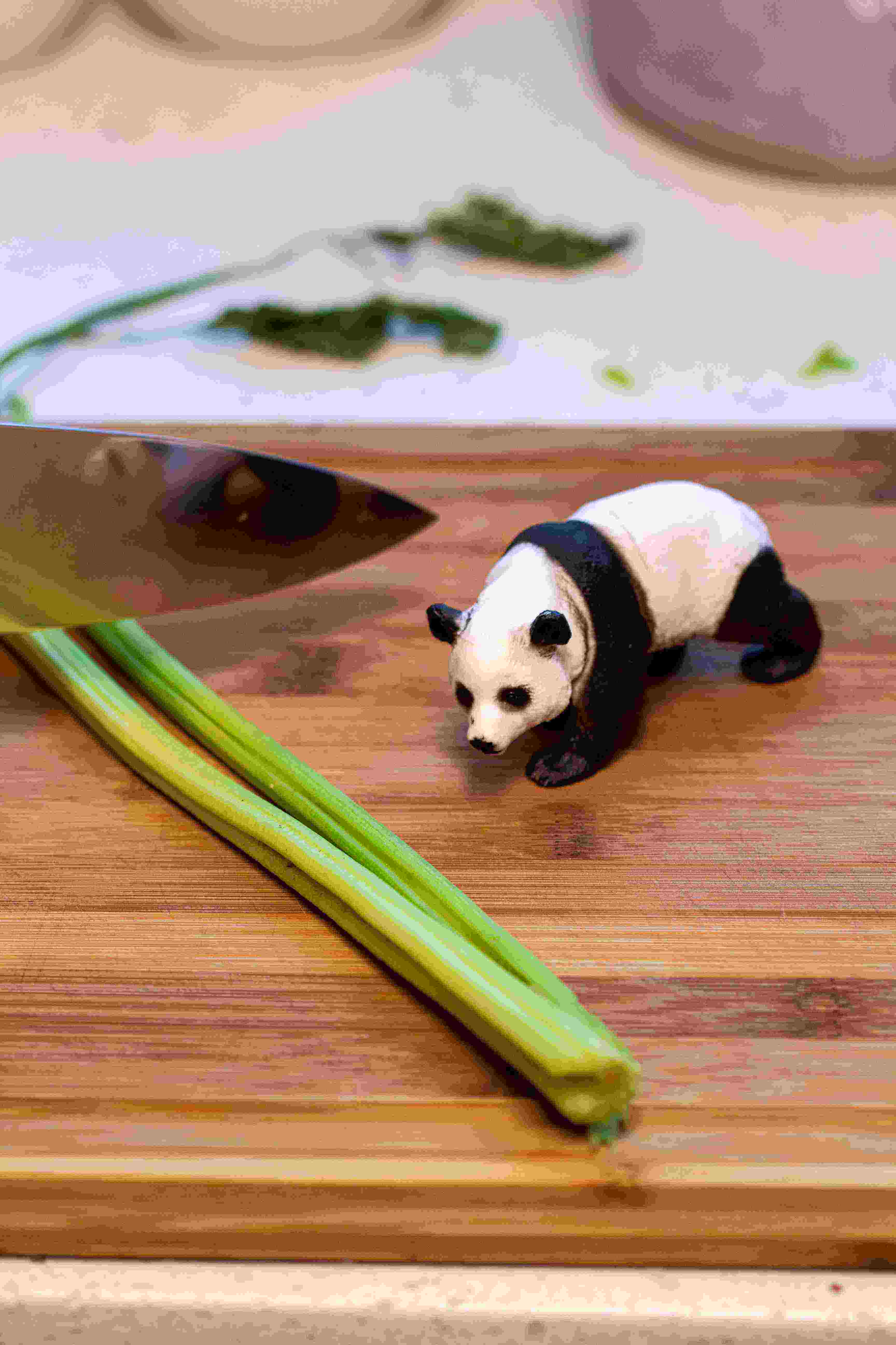 Toy panda on cutting board with knife
            and cilantro