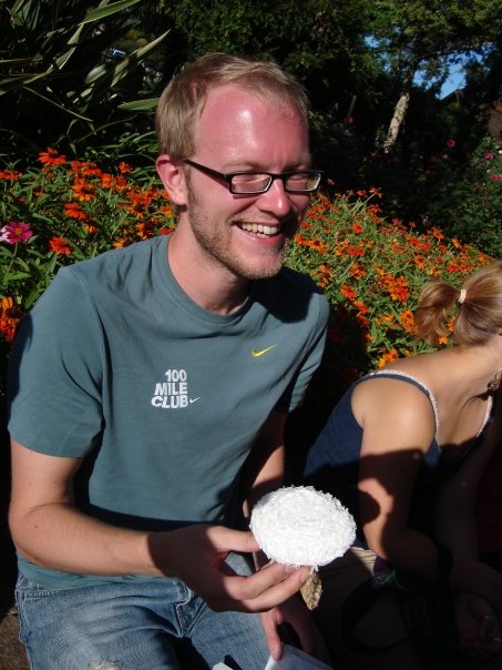 Photo of Morgan, smiling, about to enjoy a white-frosted cupcake with coconut shavings