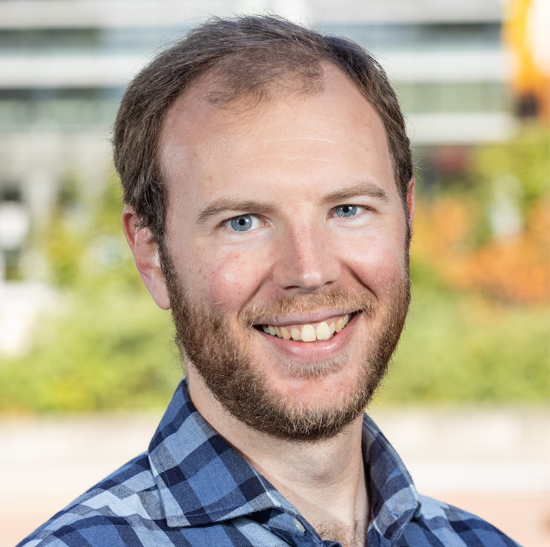 A headshot of James Wilcox looking at the camera.
            He is a white man with a beard and is wearing a blue plaid shirt.