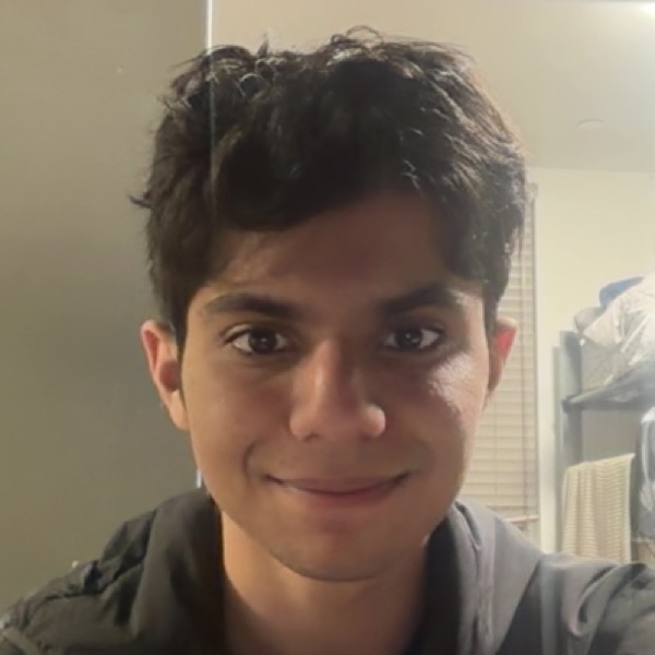 Pranav smiling at the camera in a softly lit room.