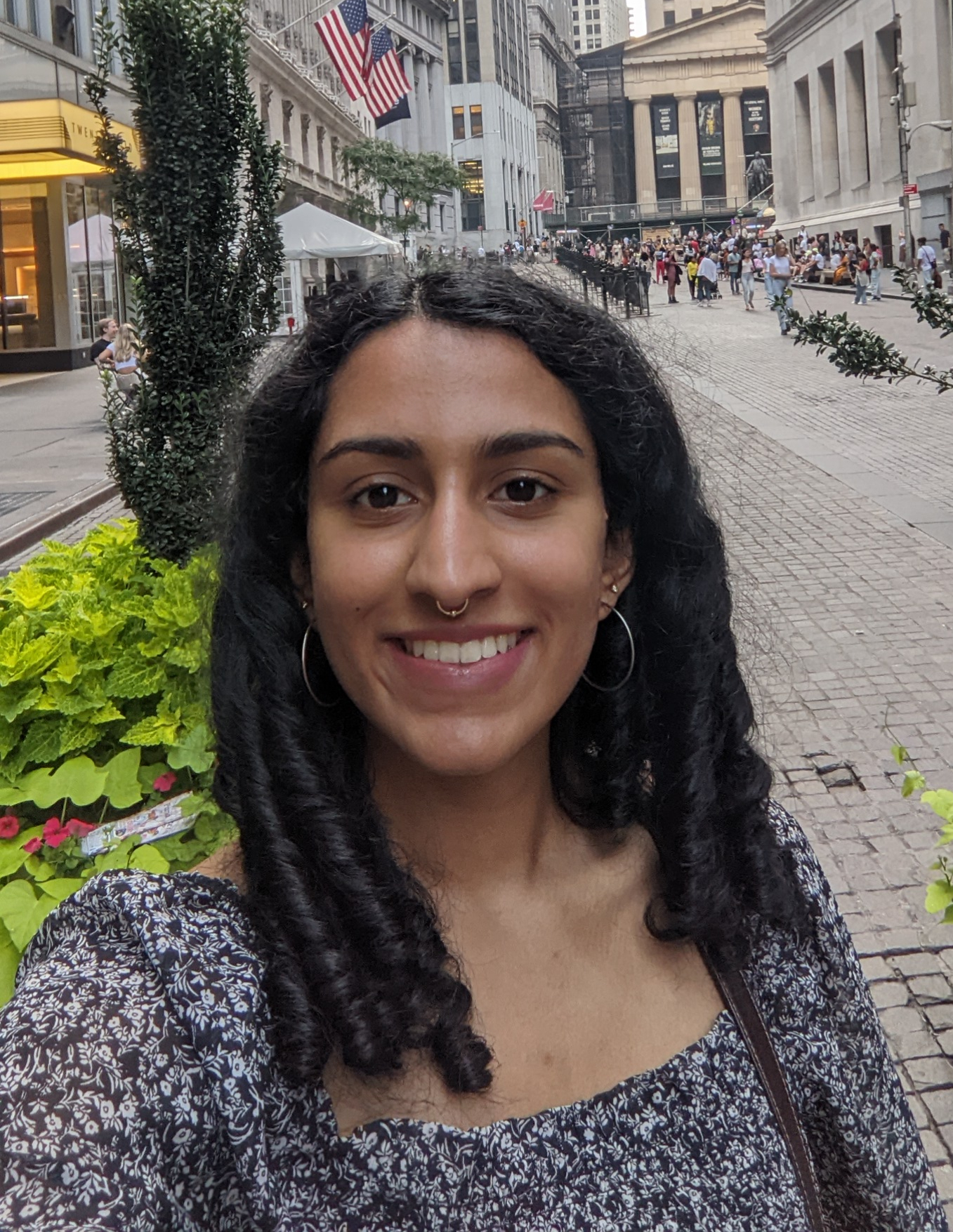 A photo of Aparna looking at the camera. She is a brown woman wearing a
    septum ring and a black blouse.