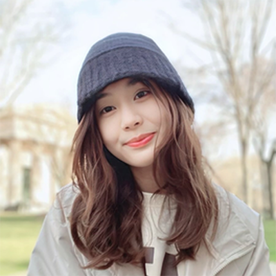 An Asian woman with wavy dark hair, wearing a dark beanie and a light jacket, smiling outdoors