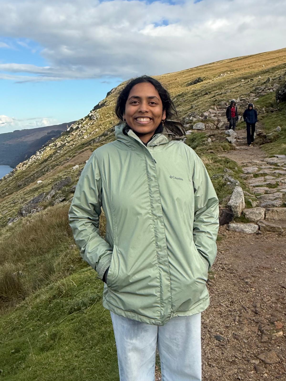 Eesha's profile picture, featuring a smiling woman in front of a grassy landscape