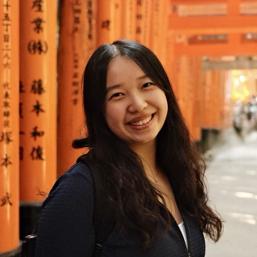 Helena's profile picture, featuring a woman with dark hair smiling in front of an orange background