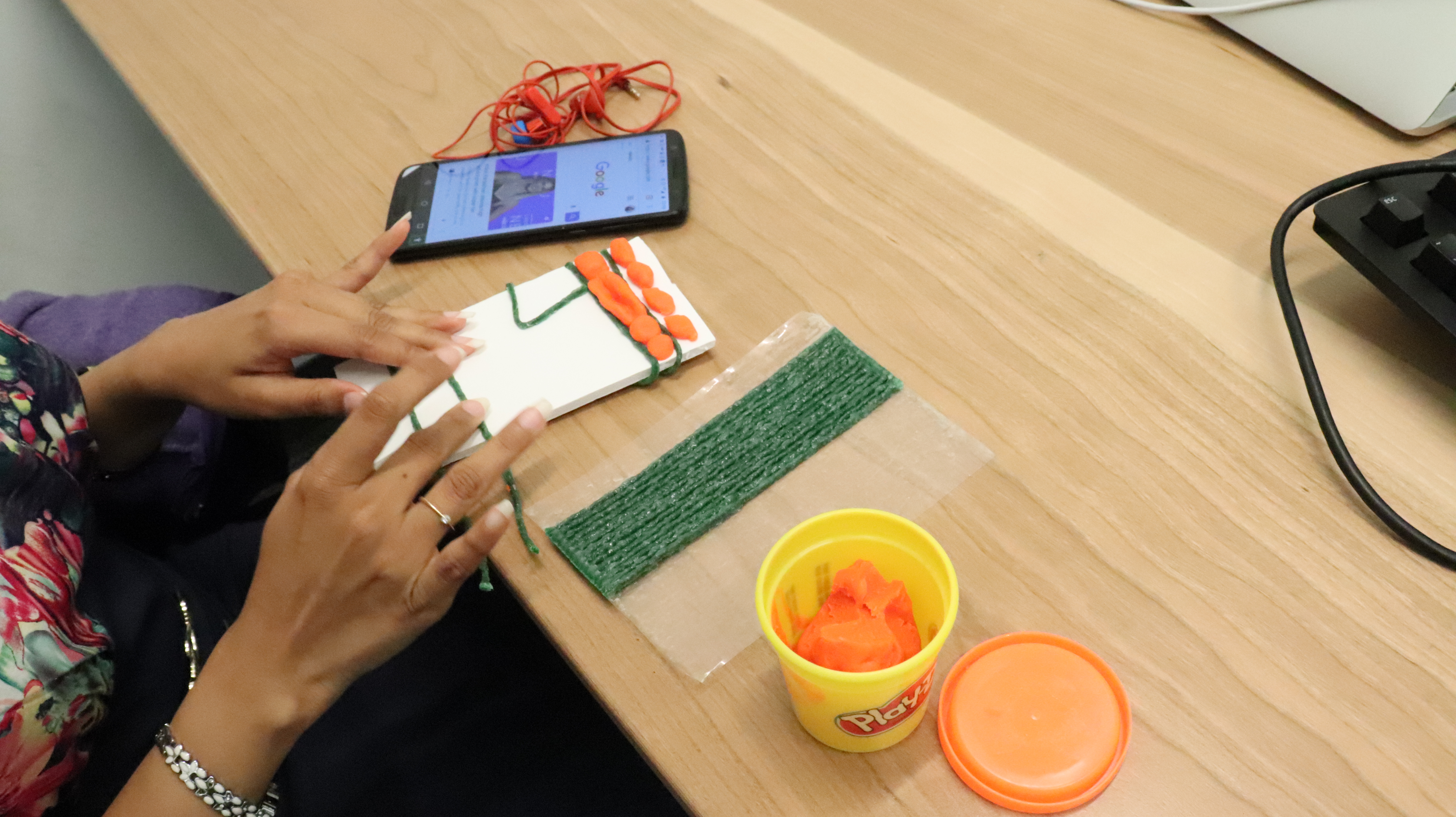 :img A piece of cardboard is decorated with wiki sticks and play dough to create tactile indicators of an interface for a blind person, 60%, height