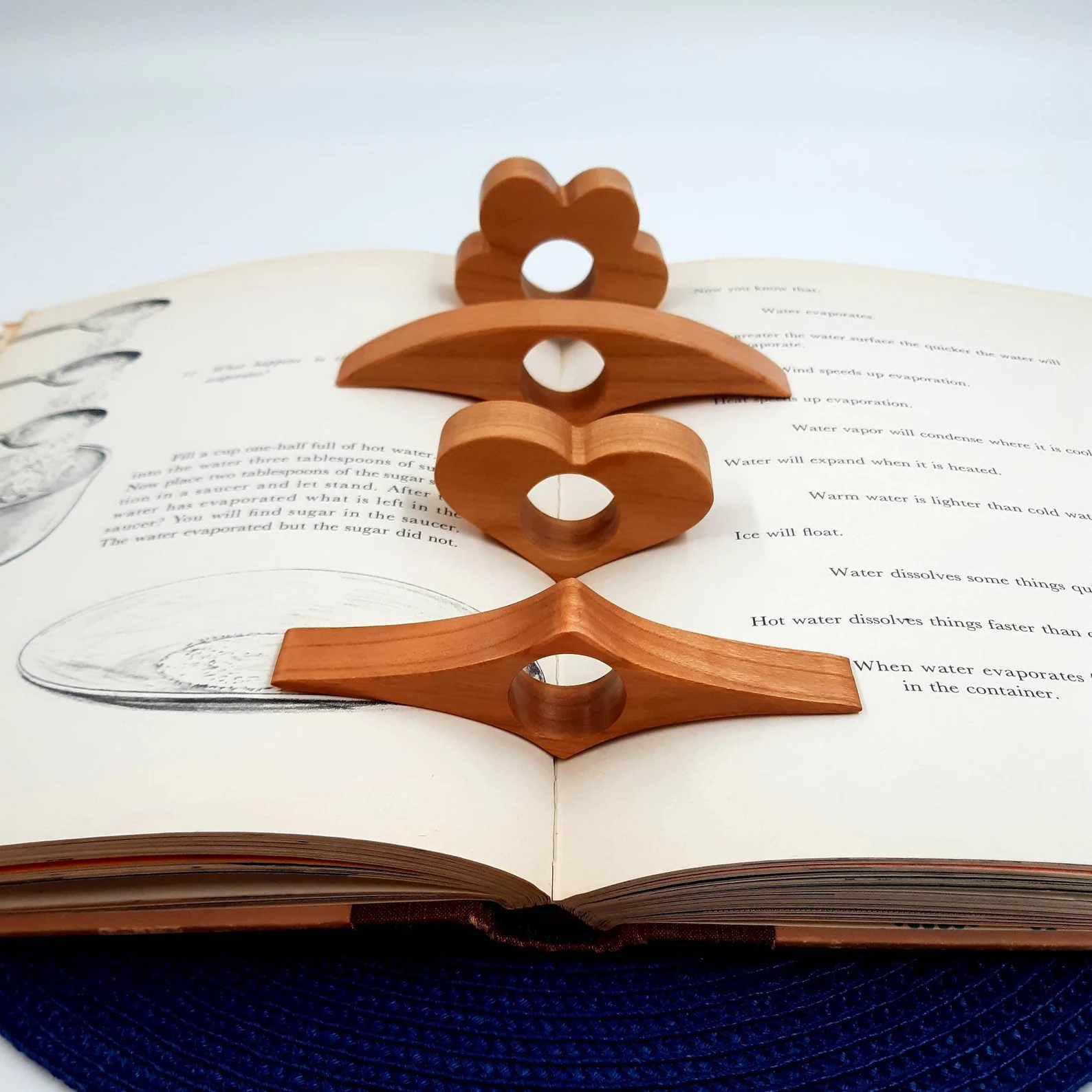 :img Wooden items decoratively shaped but all relatively wide and flat with a finger hole for holding a book open, 80%, width